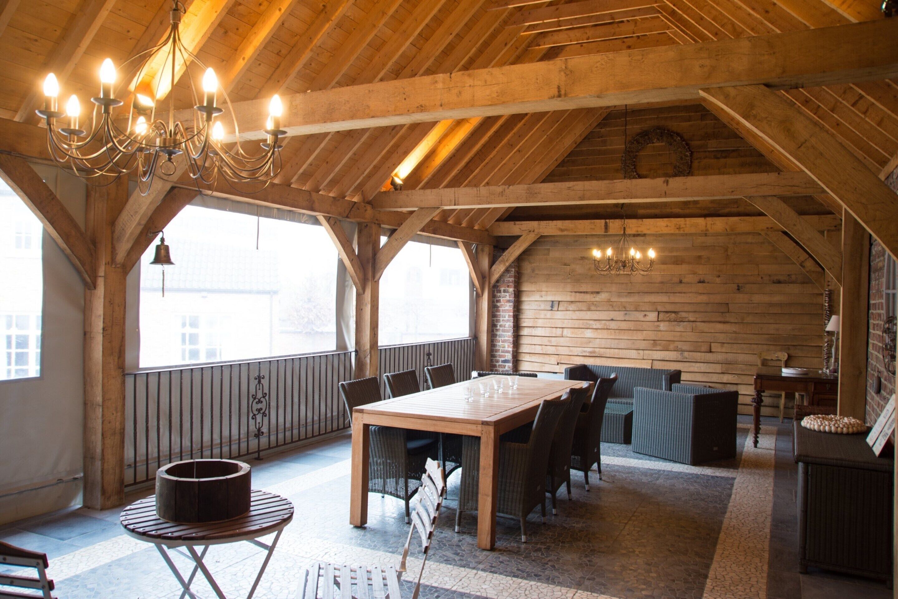 A spacious loft with exposed wooden beams, a large dining table, and a cozy seating area.