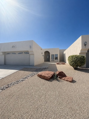 A modern building with a garage, a driveway with gravel and rocks, and a small bush.