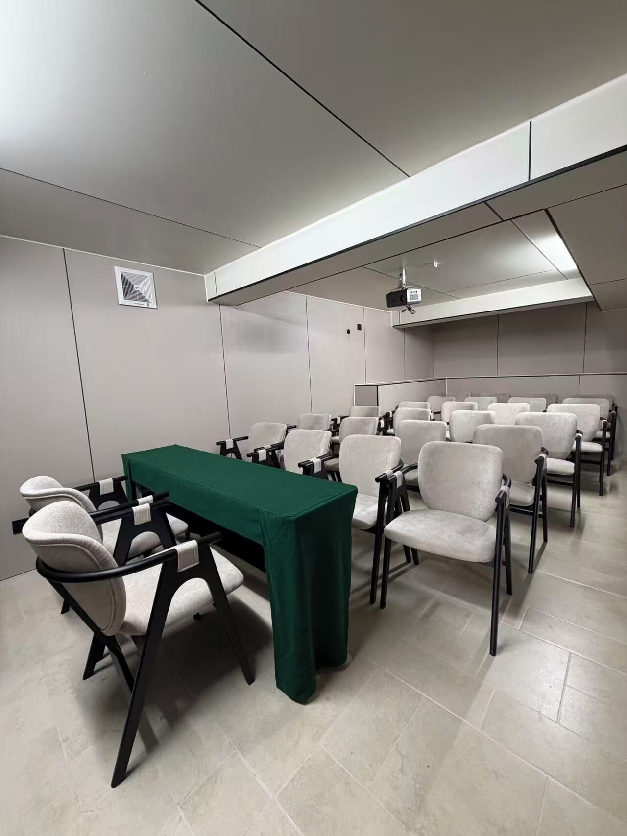 Une salle de conférence équipée d’une longue table et de nombreuses chaises, d’un projecteur et d’un écran fixé au plafond.