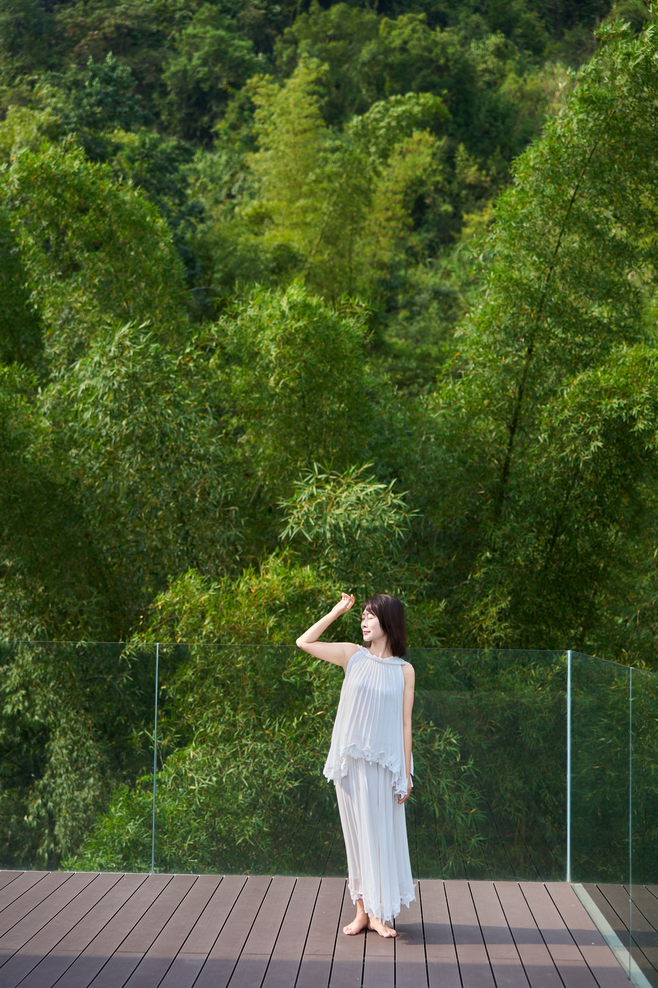Una persona de pie sobre una terraza de madera, con un bosque al fondo.