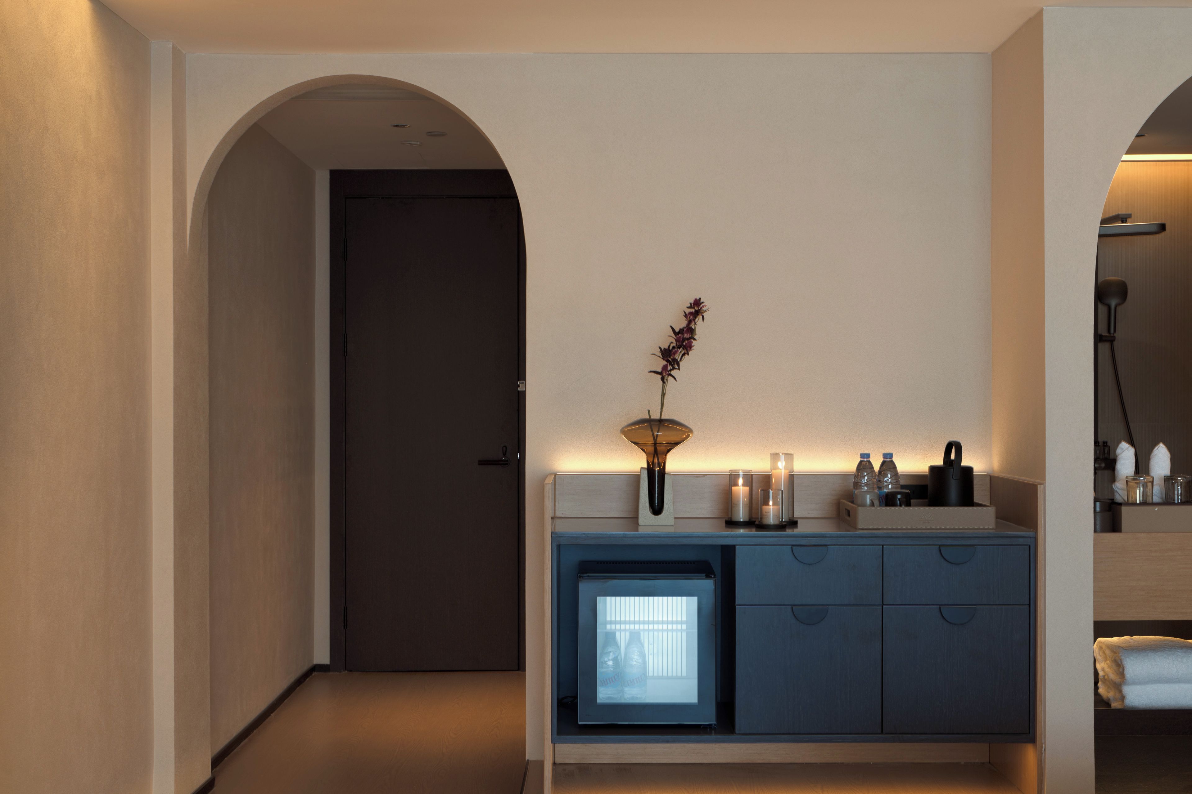 Une salle de bain moderne avec un meuble-lavabo bleu foncé, un petit réfrigérateur et un miroir au-dessus du lavabo.