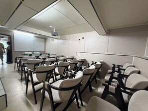 A conference room with rows of chairs, a projector, and a whiteboard.