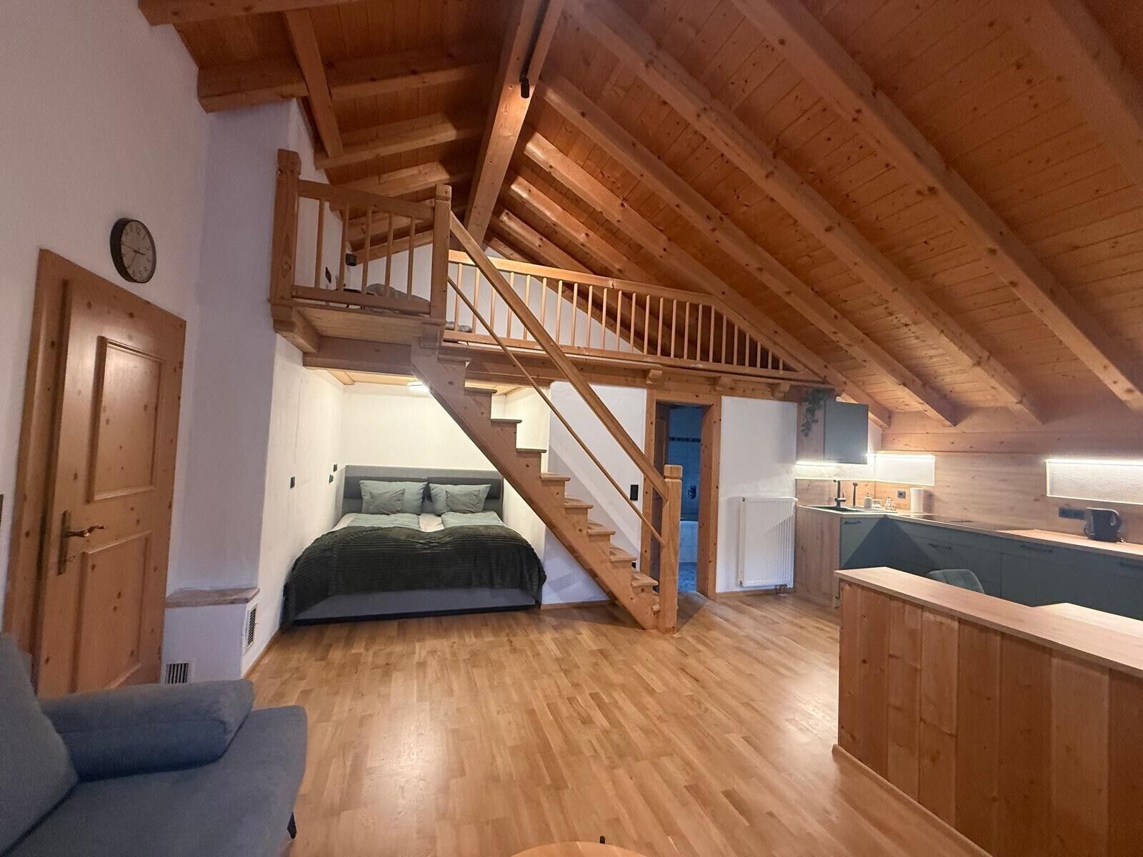 Ein Schlafzimmer im Loft-Stil mit einer Holztreppe, einem Bett und einer Küchenzeile.