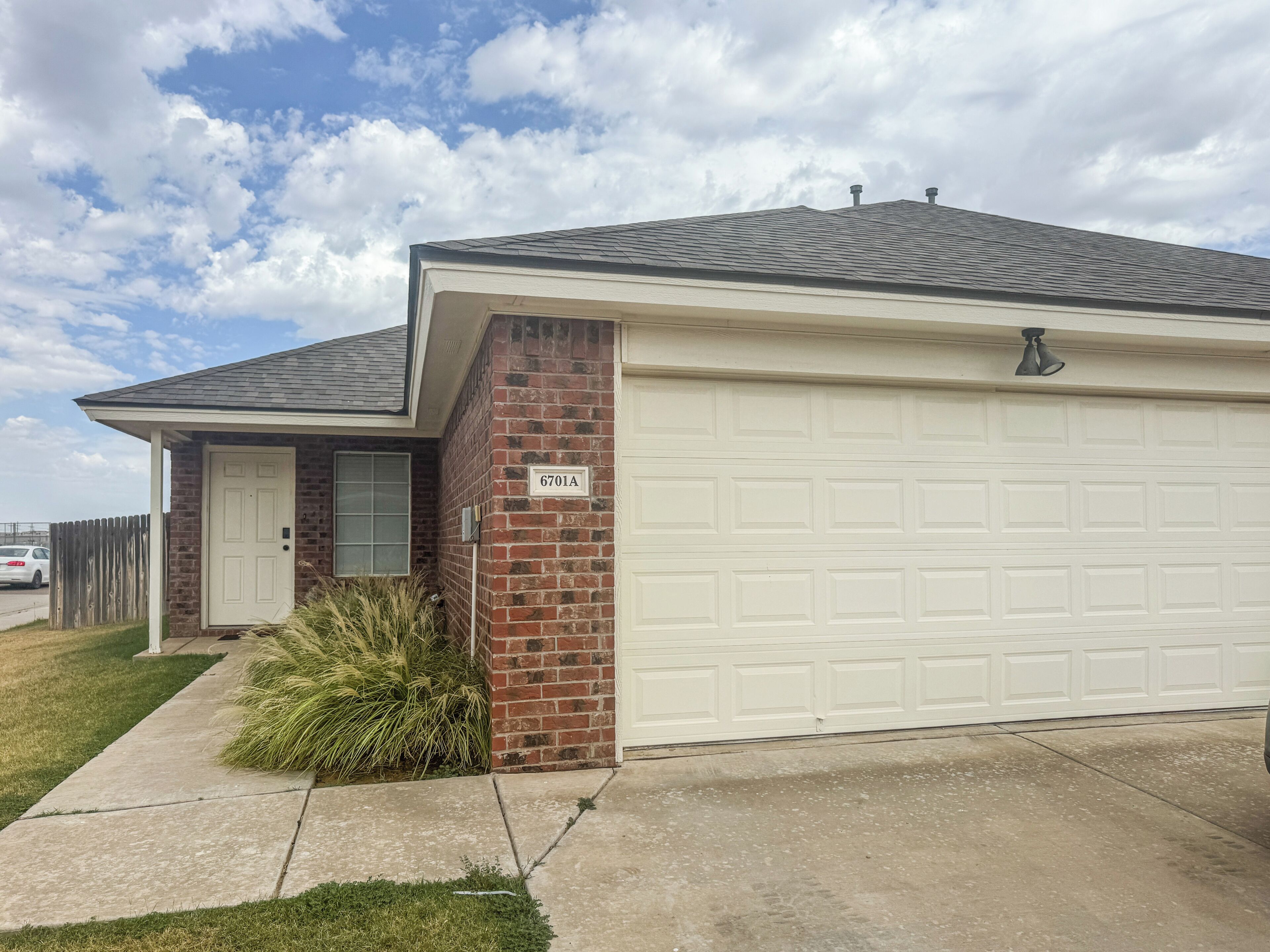 A residential house with a garage, a brick exterior, and a clear sky.
