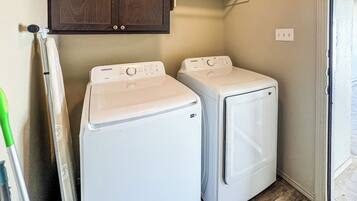 A laundry area with two white washing machines, a wooden cabinet above, and a door leading outside.