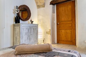 A bedroom with a bed, a wooden wardrobe, a mirror, and a wooden door.