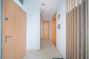 Ein Flur mit Holztüren, Fliesenboden und einer hellen Wand.