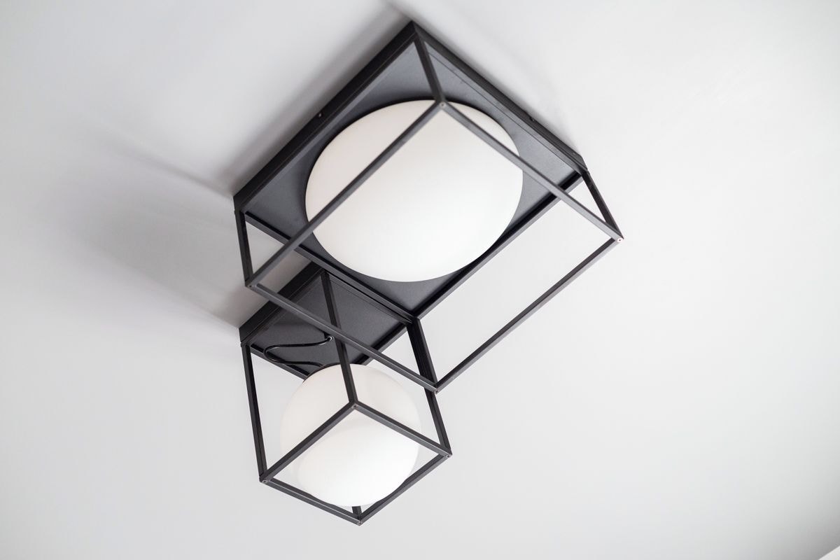 A geometric wall-mounted light fixture with a central circular element and surrounding rectangular shapes.