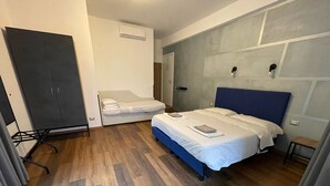 A hotel room with a bed, a chair, a wardrobe, and a door.