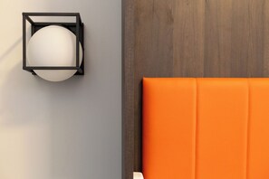 Una habitación con pared gris, panel de madera y cabecera tapizada en naranja.