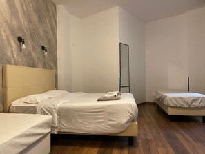 Habitación de hotel con dos camas, un espejo grande y piso de madera.