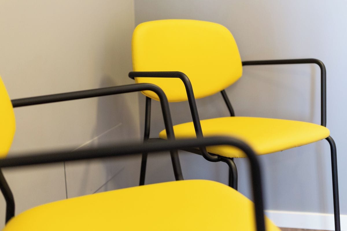 A close-up of yellow chairs with black metal frames.