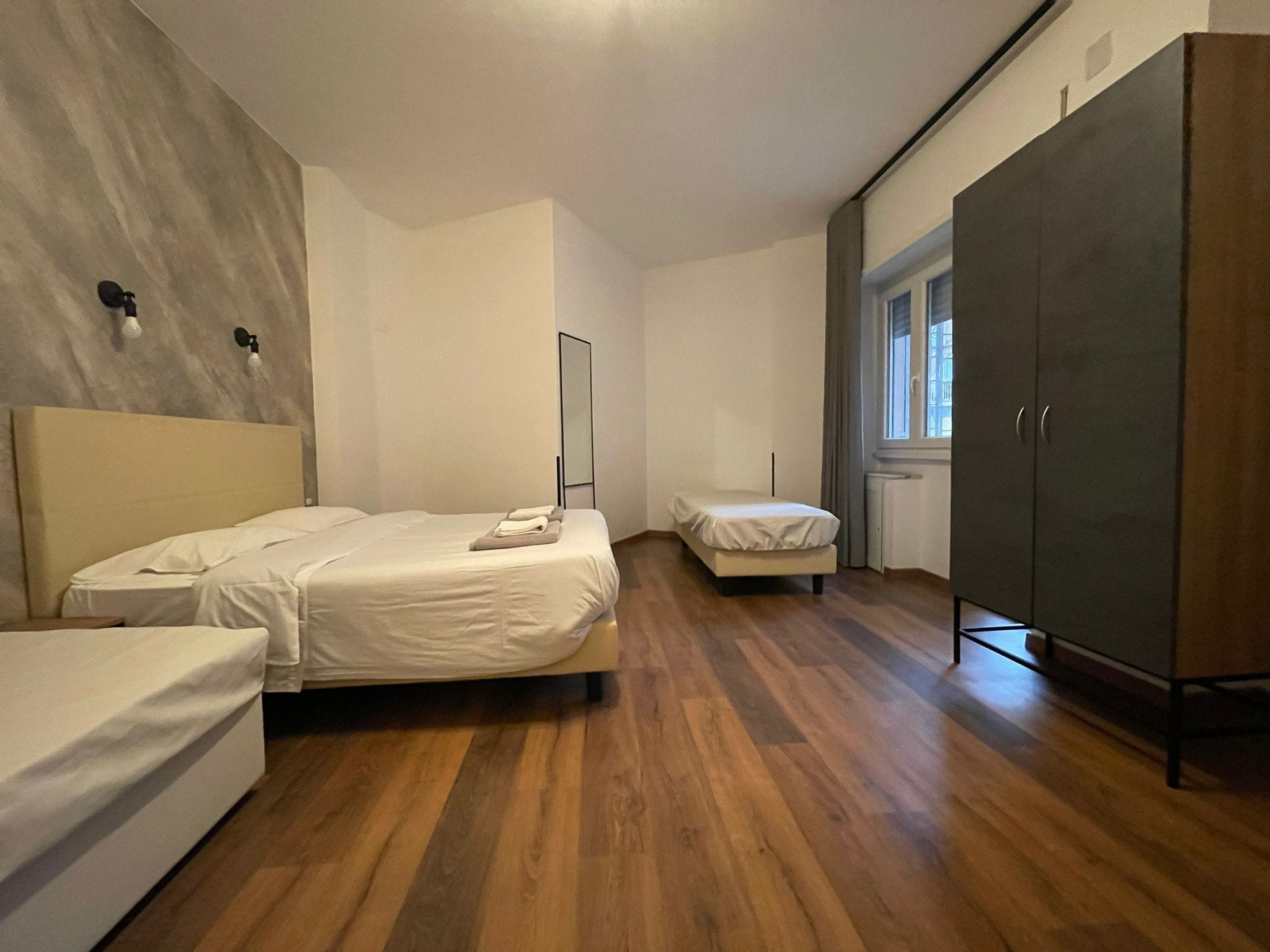 A room with two single beds, a wardrobe, and a window.