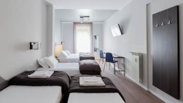 A hotel room with two beds, a desk, a chair, a TV, and a wardrobe.