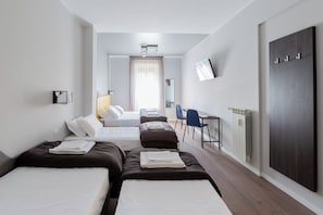Une chambre d’hôtel avec deux lits, un bureau, une chaise, une télévision et une armoire.