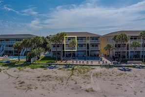 Ein mehrstöckiges Hotel mit Schwimmbad, Außenbereich und Palmen.