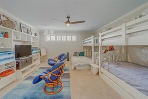 A room with bunk beds, a television, a bookshelf, and a rocking chair. - Welcoming 3-bedroom Beachfront Condo in Belleair Beach (Belleair Beach)