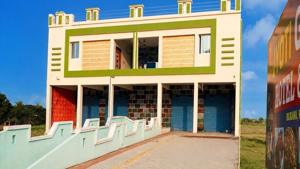 Um edifício de dois andares com telhado plano, entrada central e área coberta com uma porta vermelha.