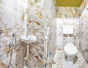 Een badkamer met wanden in marmerlook, een witte wastafel en een toilet.
