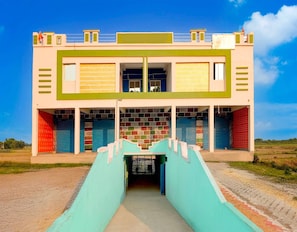 Een gebouw met twee verdiepingen en een centrale trap naar een overdekte ingang.
