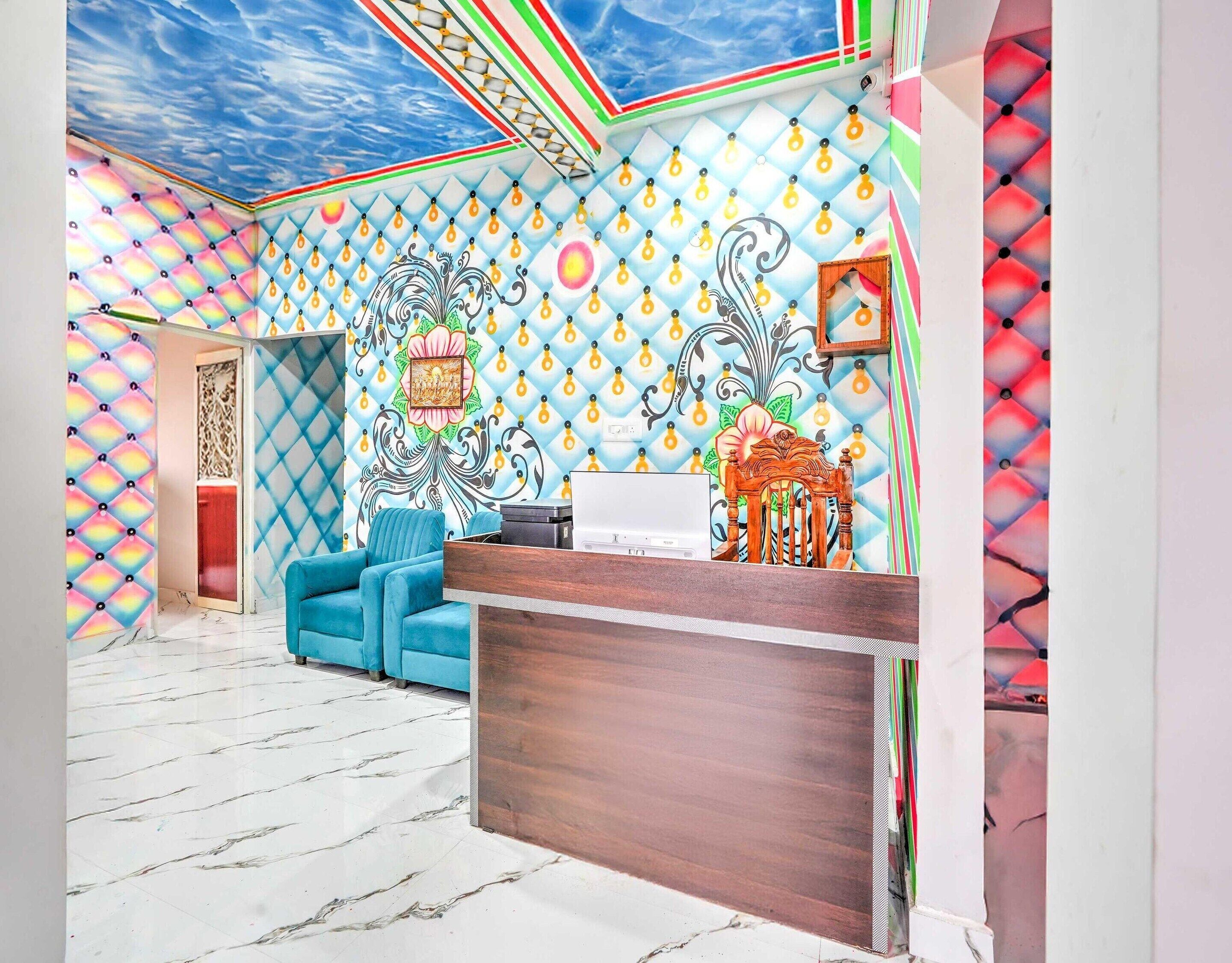 A room with a patterned ceiling, a blue sofa, a wooden reception desk, and a decorative wall.