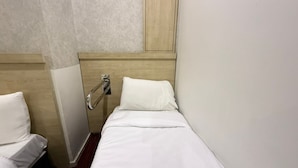 Una habitación de hotel con una cama, un pasamanos y un cabecero de madera.