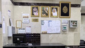 Un mostrador de recepción con fotografías enmarcadas, una planta y carteles informativos.