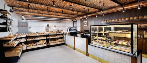 A bakery with a brick ceiling, wooden counters, and a glass display case filled with pastries.
