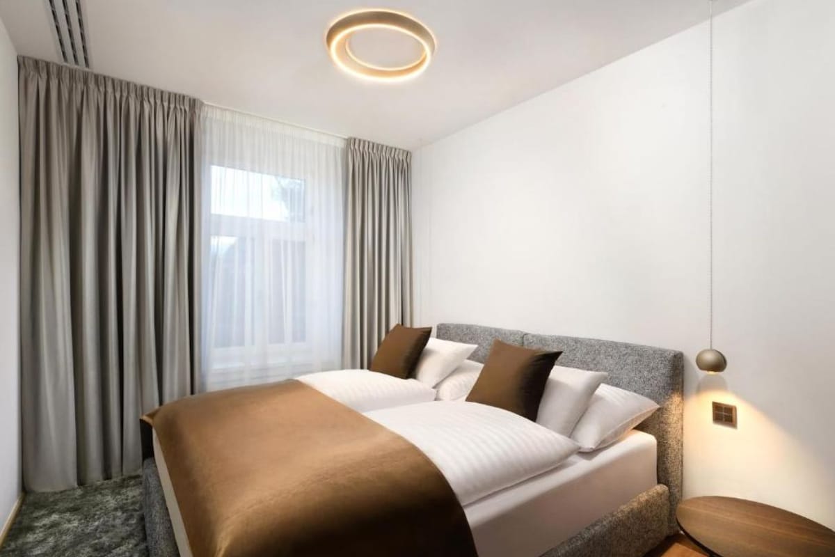 Ein modernes Hotelzimmer mit einem großen Bett, einem Nachttisch und einer Deckenleuchte.