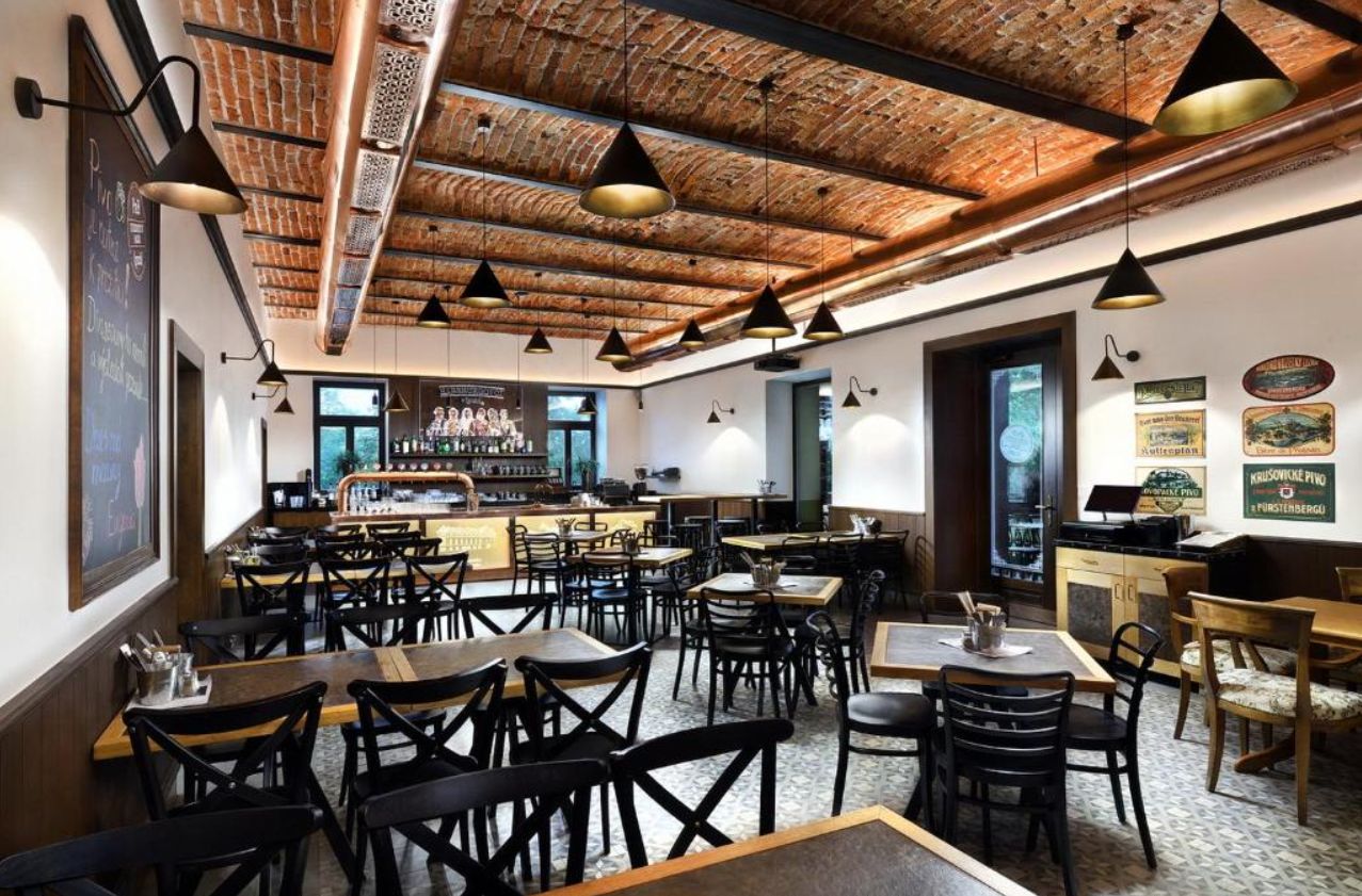 A restaurant with a brick ceiling, multiple tables, and chairs.