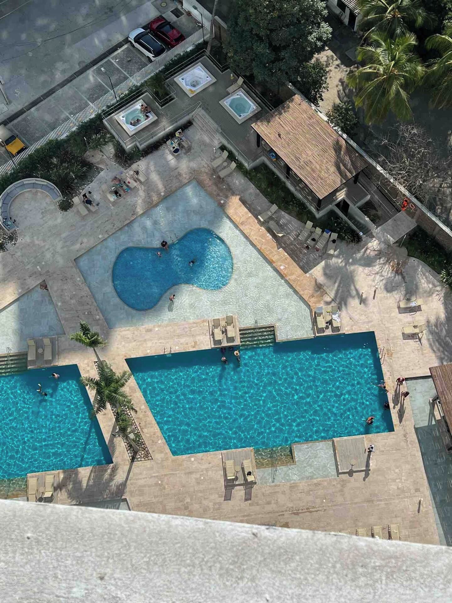 A rooftop pool area with two rectangular pools and a hot tub.