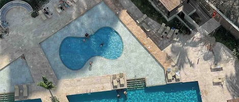 A rooftop pool area with two rectangular pools and a hot tub.