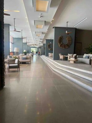 Eine geräumige Lobby mit hoher Decke, moderner Beleuchtung und einer zentralen Sitzecke mit Sofas und Sesseln.