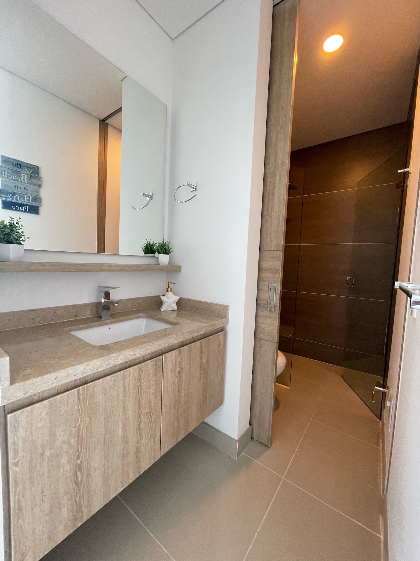 Une salle de bain moderne avec un meuble-lavabo en bois, un grand miroir et un espace douche.