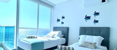 Habitación de hotel moderna con dos camas, un ventanal con vistas y un balcón.