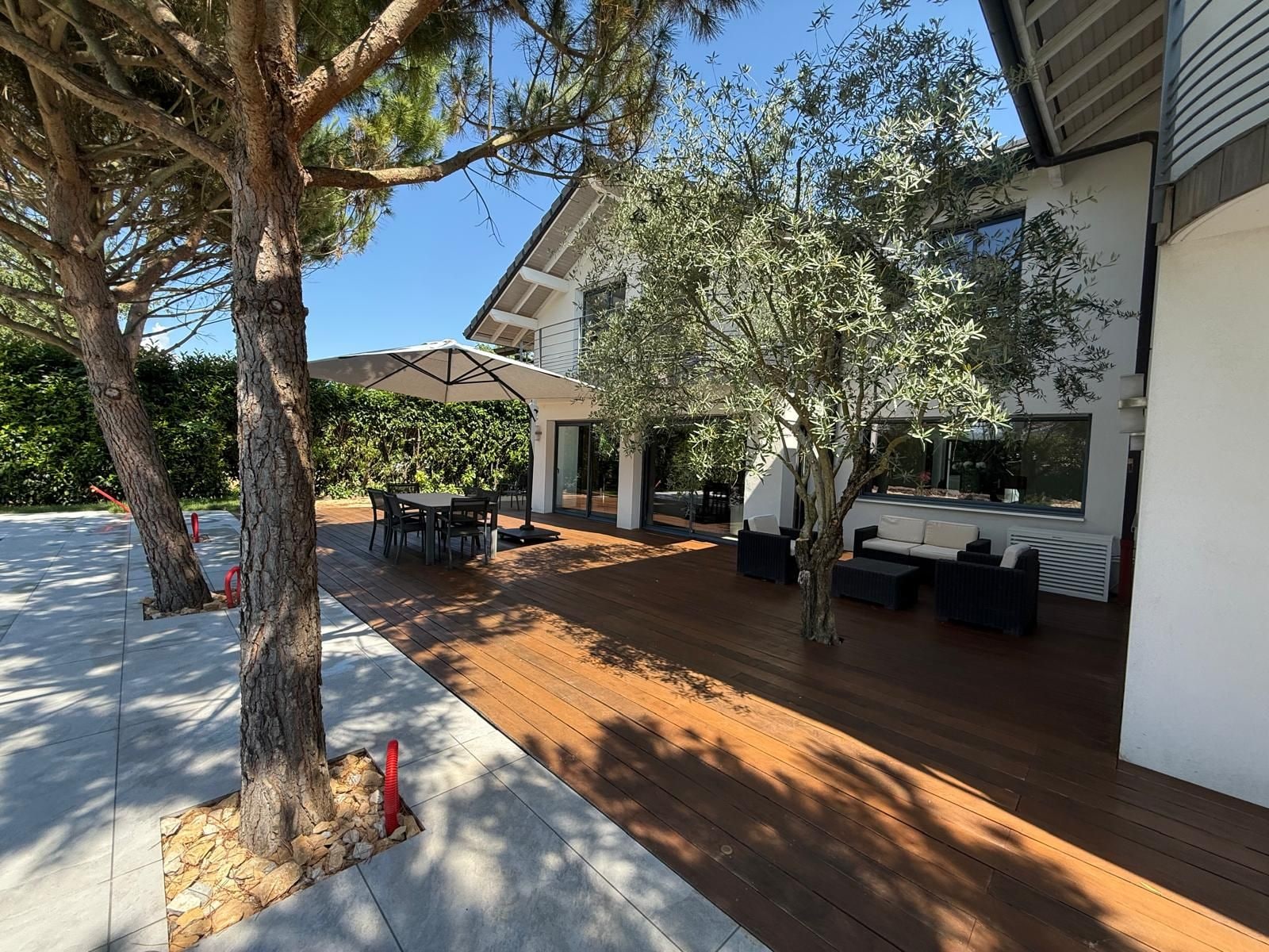 Une terrasse extérieure moderne, dotée d’une plateforme en bois, d’un espace repas et d’un coin salon.
