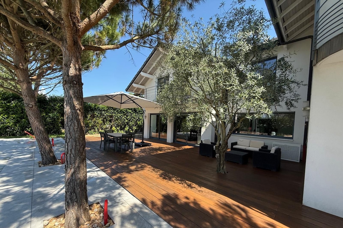 A modern outdoor patio with a wooden deck, a dining area, and a seating arrangement.