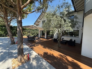 A modern outdoor patio with a wooden deck, a dining area, and a seating arrangement.