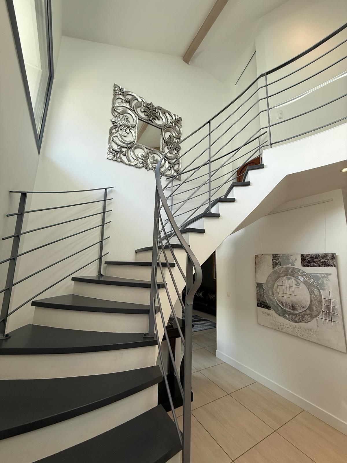 Un escalier au design moderne, doté d’une rampe en métal et d’un élément décoratif mural.