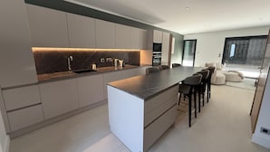 A modern kitchen with a central island, built-in appliances, and a seating area with a sofa and chairs. - RIVAGES BAY (Veigy-Foncenex)