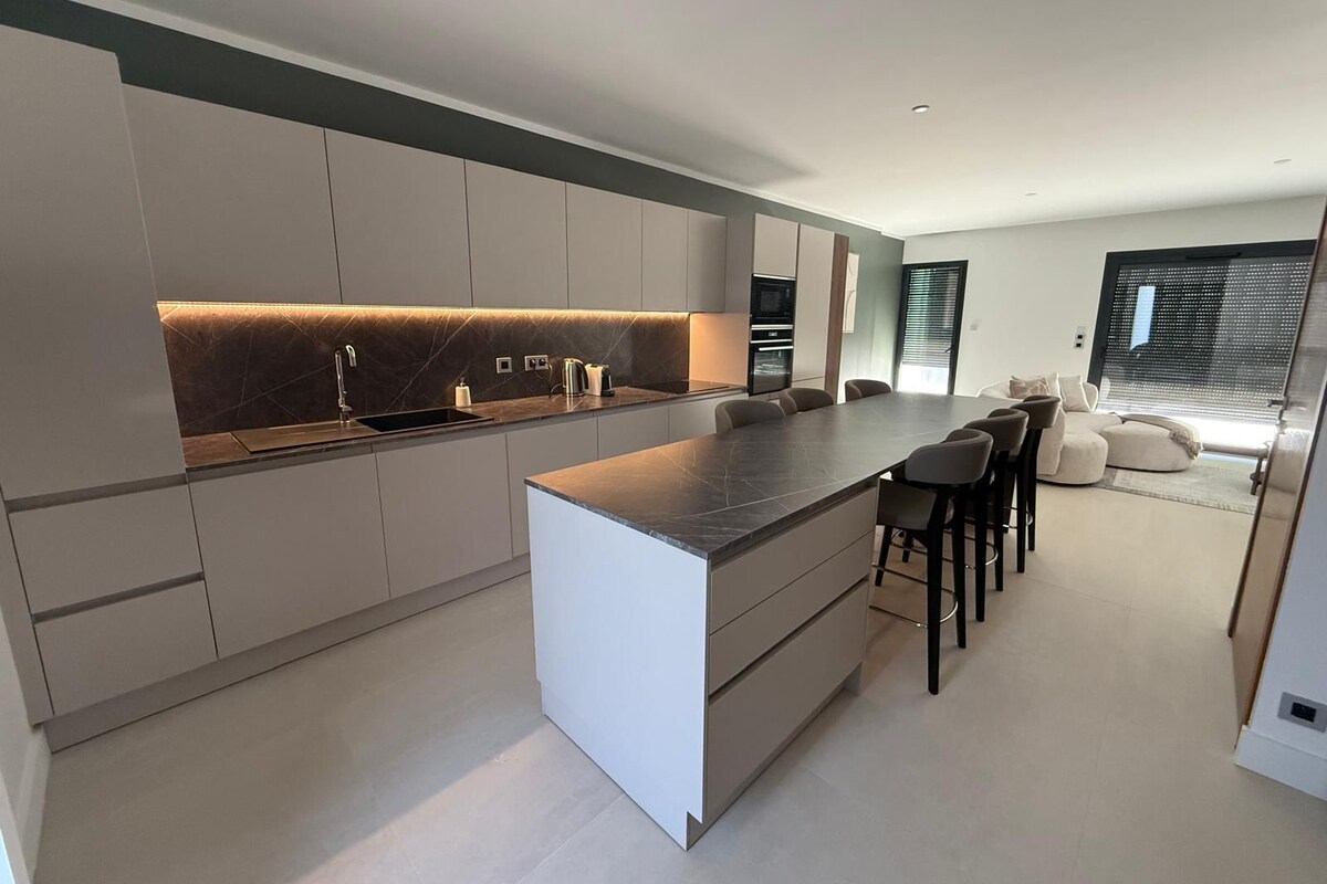 A modern kitchen with a central island, built-in appliances, and a seating area with a sofa and chairs.
