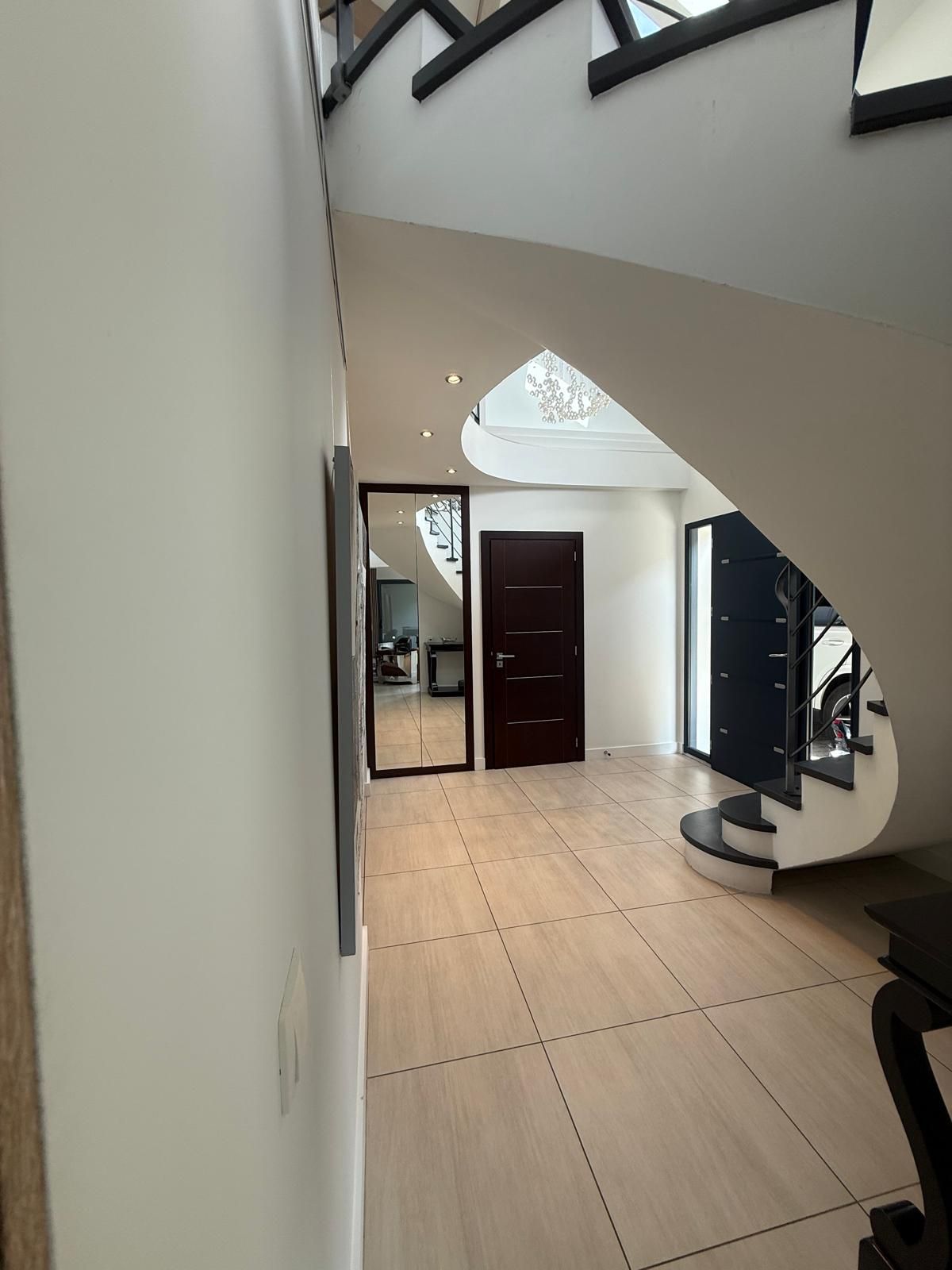 A spacious room with a modern staircase, a large window, and a door leading to another area.