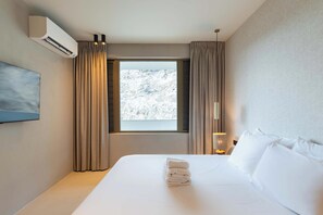 Ein Hotelzimmer mit Bett, einem fenster mit Vorhängen, einer Klimaanlage und einer wandmontierten Lampe.