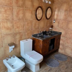 A bathroom with a toilet, bidet, and sink. There are two mirrors on the wall and a towel rack.