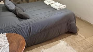 Un dormitorio con cama, televisor de pantalla plana, espejo y ventana con cortinas.