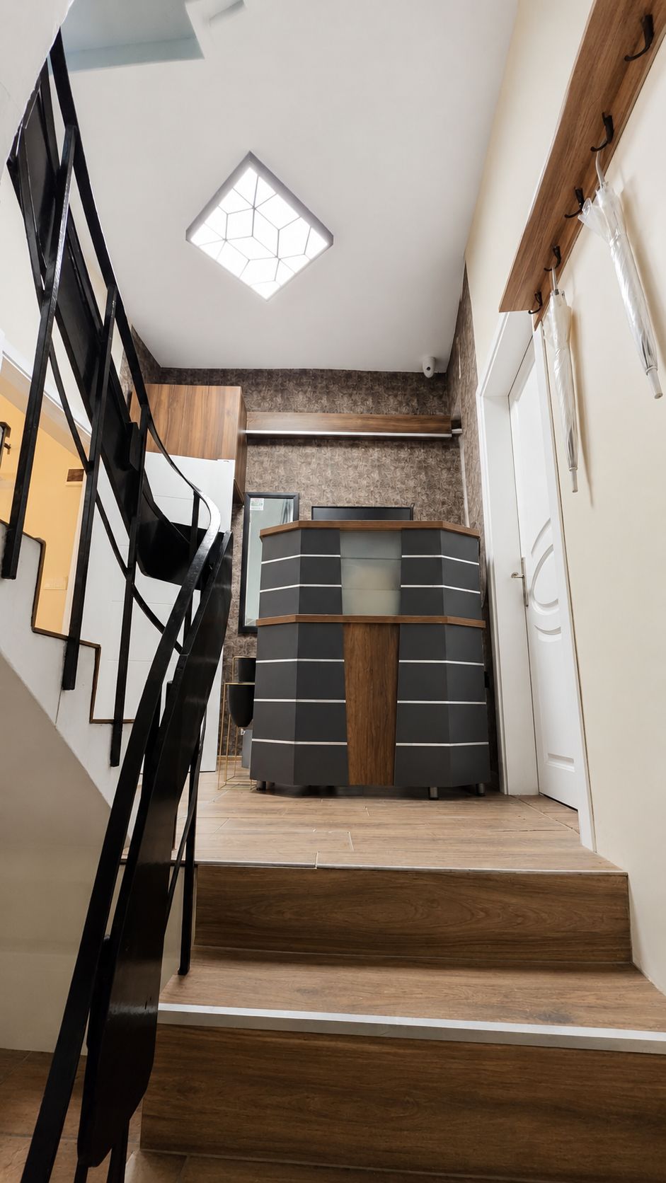 Una escalera conduce a una habitación de diseño moderno, con suelo de madera y tragaluces en el techo.