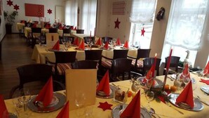 Un ristorante con tavoli apparecchiati per la cena, con tovaglioli rossi e candele.