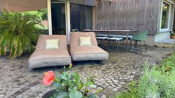 A modern outdoor seating area with two cushioned chairs, a table, and a potted plant.