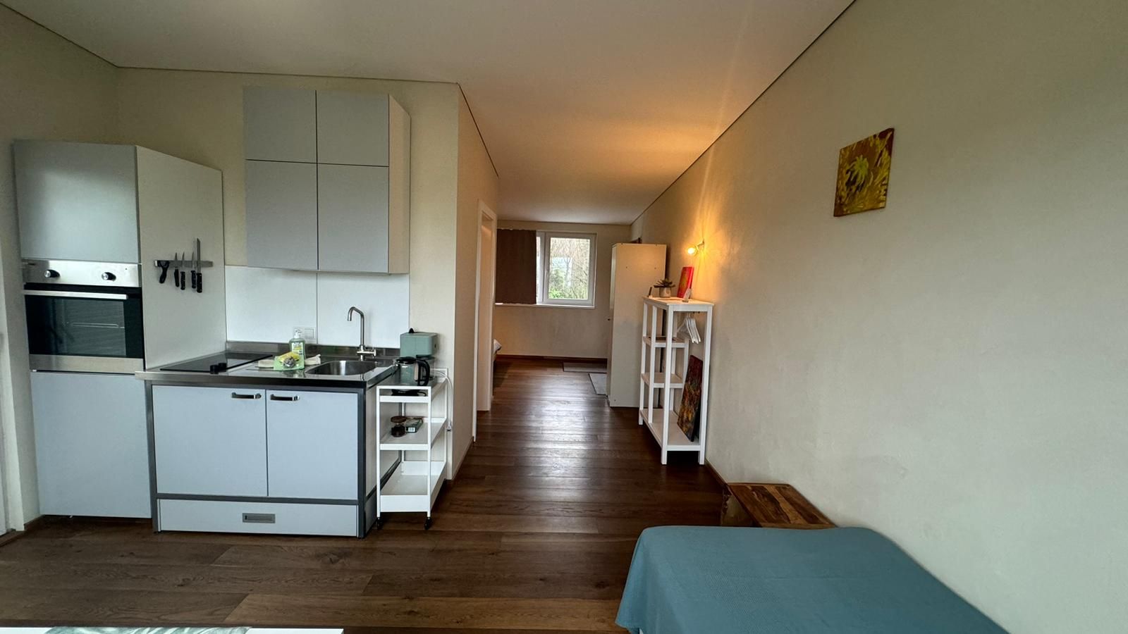 A compact kitchen with white cabinets, a built-in oven, and a sink.