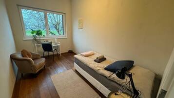 Une petite pièce comprenant un lit, une chaise, un bureau et une fenêtre.